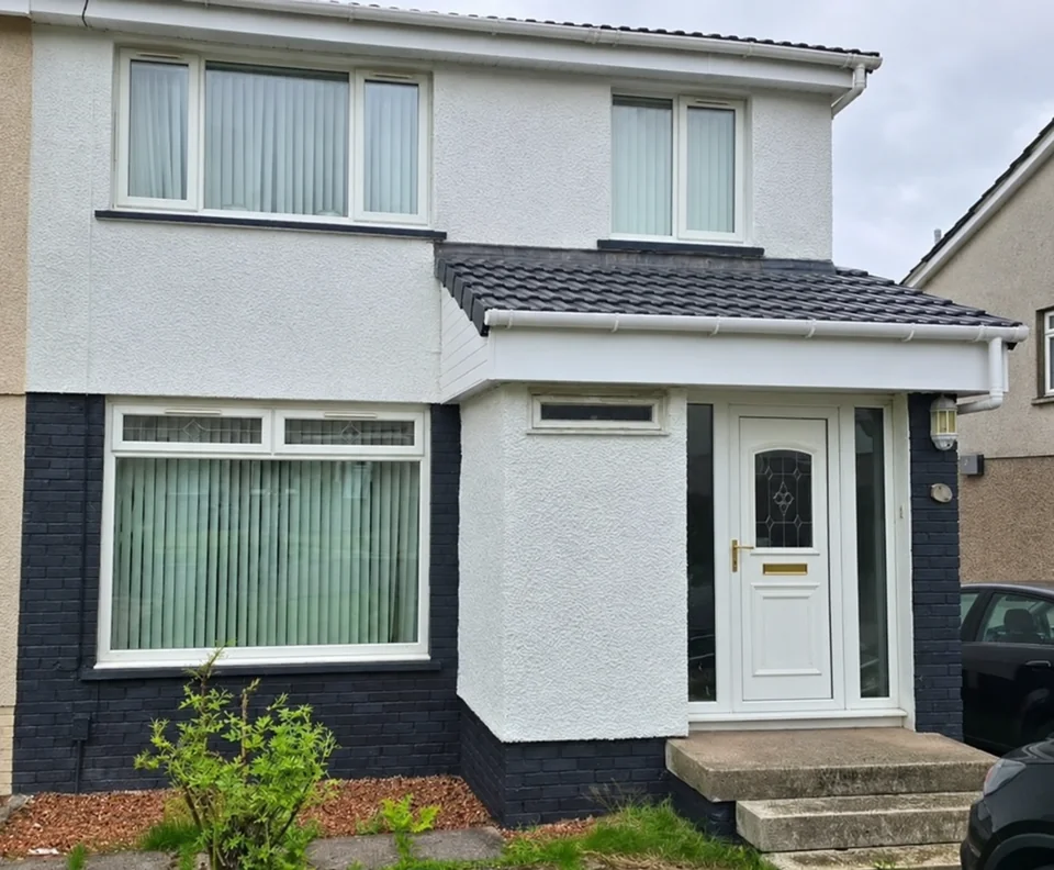 Pale coated house exterior with dark window surrounds